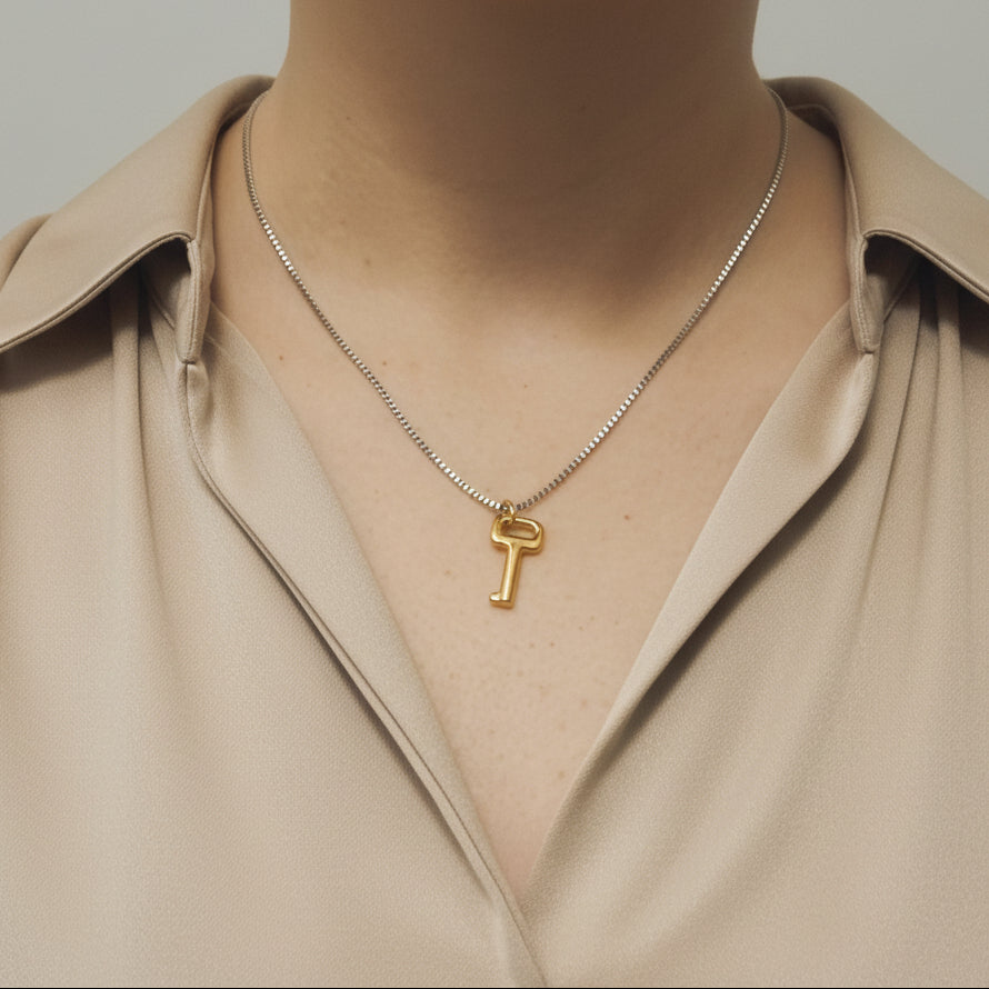 plan d'un buste féminin portant un collier avec un pendentif en forme de clé. La chaine est couleur argent et le pendentif est couleur doré