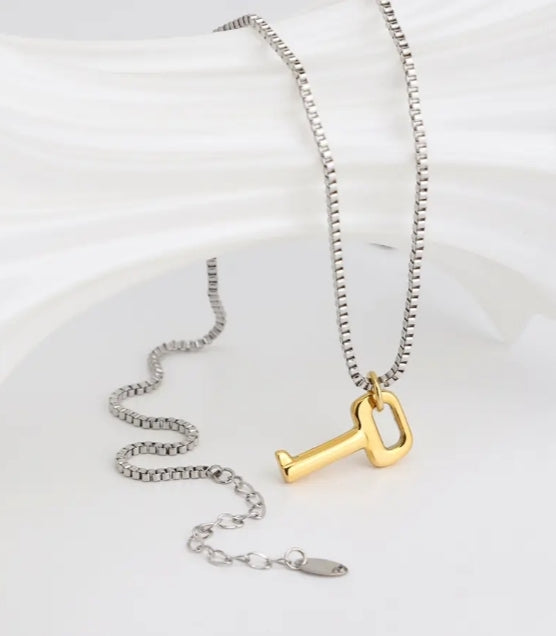 vue d'un bijoux mis en valeur, le collier avec pendentif (la chaine est argenté, et le pendentif en forme de clé est doré)