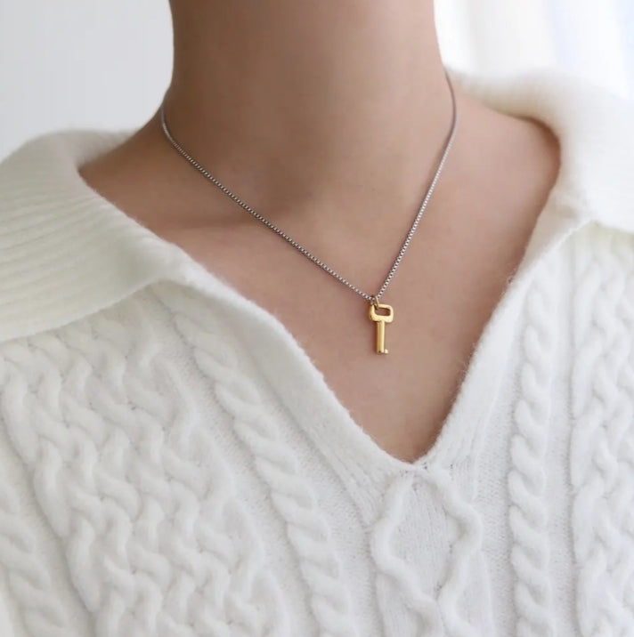 plan d'un buste féminin portant un collier avec un pendentif en forme de clé. La chaine est couleur argent et le pendentif est couleur doré
